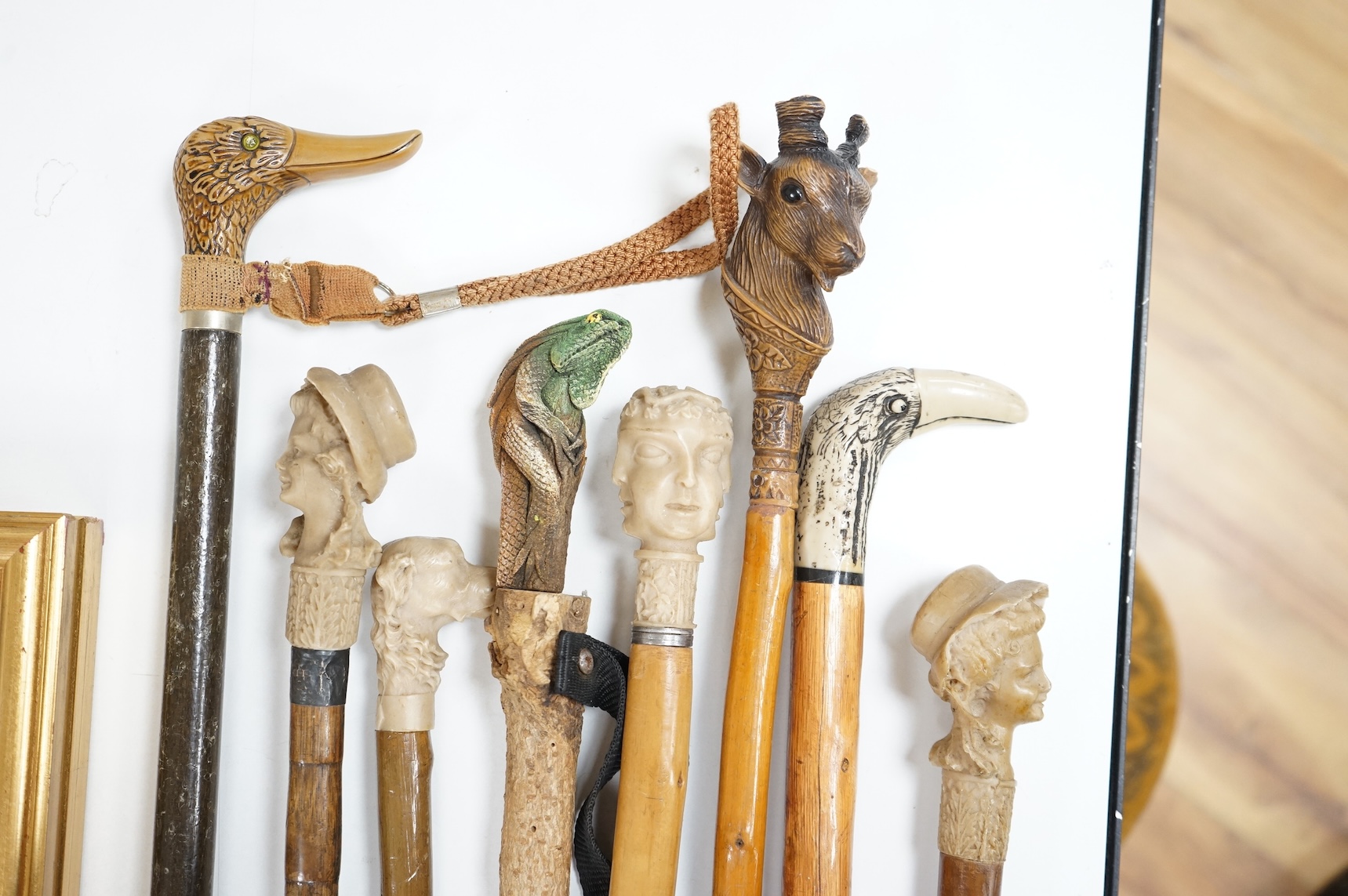 A collection of eight mostly moulded resin mounted walking canes to include one in the form of a lizard, largest 93cm in length